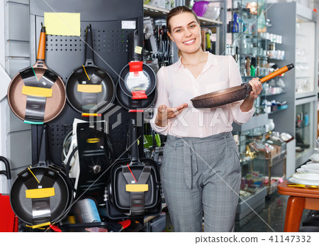 Young female buyer choosing new pan for kitchen in the dishes store 41147332