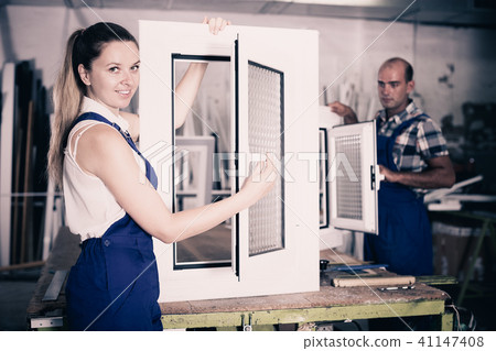 Craftswoman in blue overalls demonstrating pvc window Craftswoman in blue overalls demonstrating pvc window 41147408