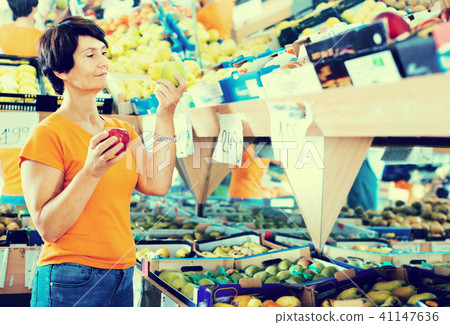 Smiling female is choosing apples in the supermarket. 41147636