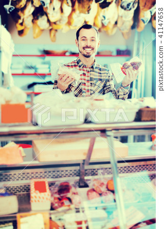 Smiling male seller showing sorts of meat Smiling male seller showing sorts of meat 41147658