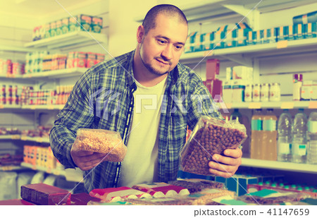 Male customer choosing nuts and grain in average food shop Male customer choosing nuts and grain in average food shop 41147659