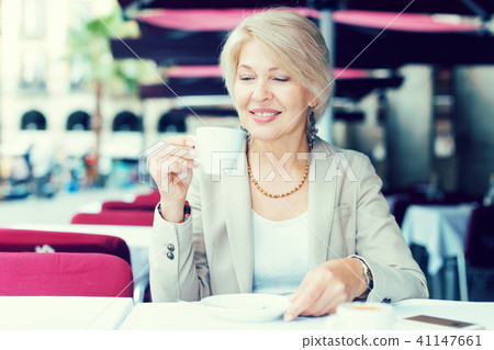 Mature woman 50s years old is lunching with coffee Mature woman 50s years old is lunching with coffee 41147661