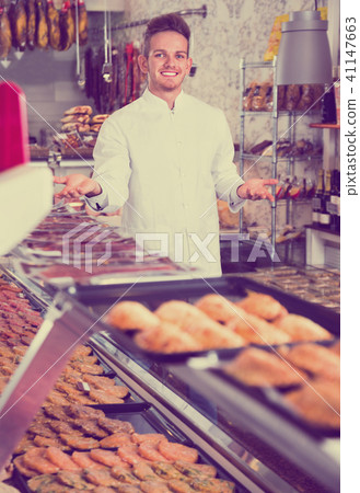 Assistant in grocery shop greeting customers Assistant in grocery shop greeting customers 41147663