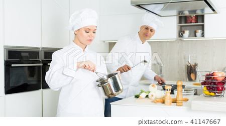 Portrait of the woman proffesional who is cooking soup in pot in the kitchen 41147667