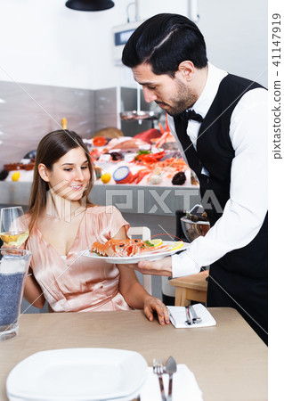 Waiter bringing seafood to woman 41147919