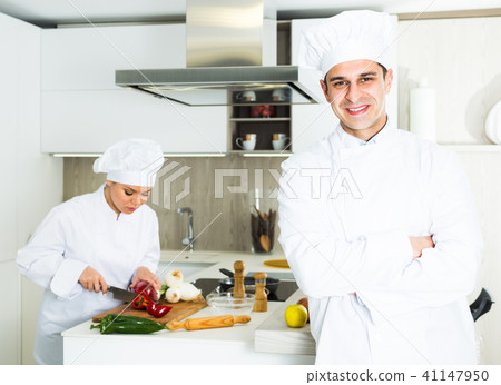 Male chef in white uniform standing near workplace on kitchen Male chef in white uniform standing near workplace on kitchen 41147950