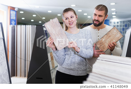Positive couple holding sample of kitchen ceramic tile 41148049