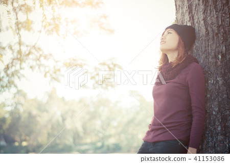 Happy beautiful woman leaning against a tree Happy beautiful woman leaning against a tree 41153086