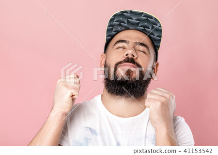 Young cheerful bearded football fan in cap celebrating 41153542