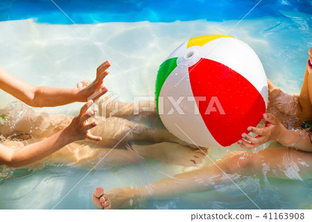 hands of little boy and girl playing with Multi Colored Beach ball in swimming pool hands of little boy and girl playing with Multi Colored Beach ball in swimming pool 41163908