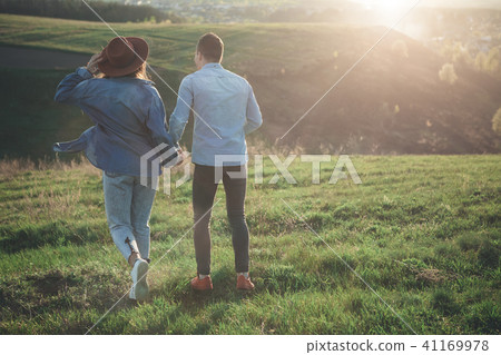 Couple walking on green hill in warm summer evening Couple walking on green hill in warm summer evening 41169978