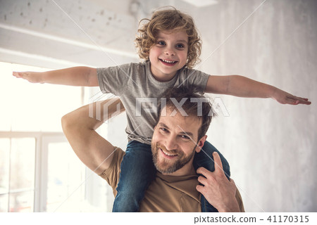 Grinning father is carefully raising son on shoulders 41170315