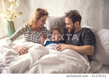 Cheerful parents are embracing son while staying in bed linen 41170332