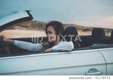 Happy young woman is driving a convertible car  41170753