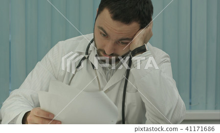Tired medical doctor tired from paper work with documents Tired medical doctor tired from paper work with documents 41171686