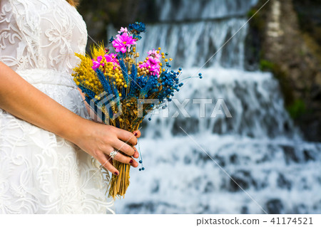 Bride holding wedding bouquet in front of a waterfall Bride holding wedding bouquet in front of a waterfall 41174521