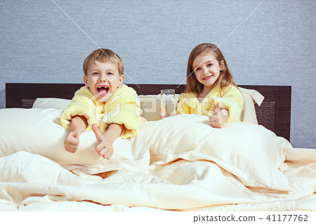 Happy laughing kids, boy and girl in soft bathrobe after bath play on white bed Happy laughing kids, boy and girl in soft bathrobe after bath play on white bed 41177762