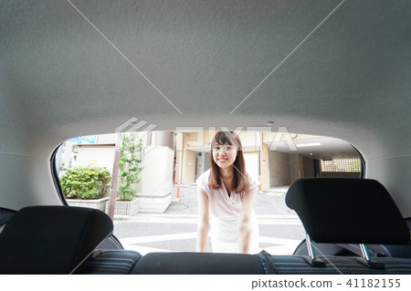 A woman who opens a trunk of a car 41182155