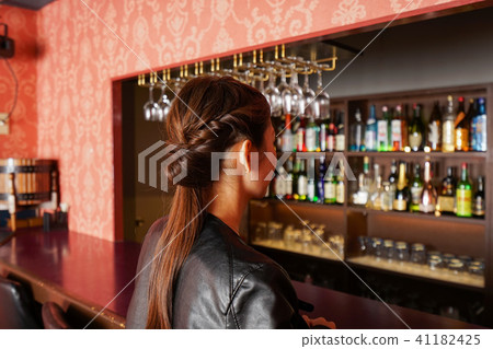 Adult woman sitting in a bar counter Adult woman sitting in a bar counter 41182425