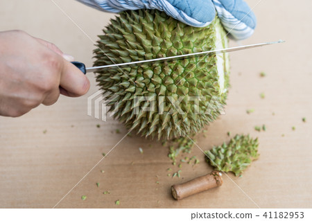 Hand using knife to peel durian. Hand using knife to peel durian. 41182953