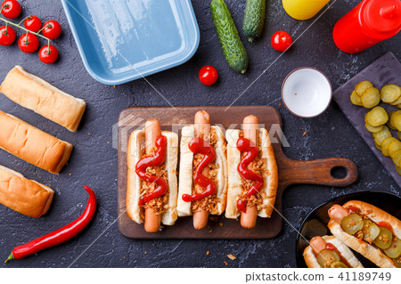 Picture on top of buns with sausages on cutting board, on table with cucumbers 41189749