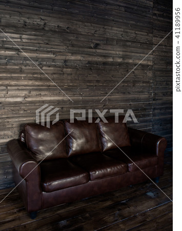 vintage brown leather sofa on a wooden wall and floor vintage brown leather sofa on a wooden wall and floor 41189956