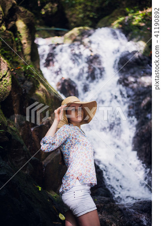 Cute woman with a hat posing by the forest waterfalls Cute woman with a hat posing by the forest waterfalls 41190892