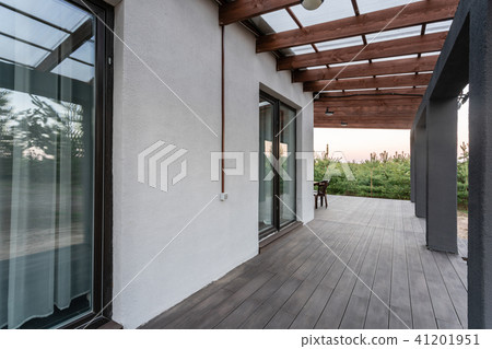 Side view of an open veranda in front of a modern forest cottage. Pine young forest under the sunset 41201951