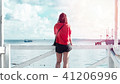Women standing on a wooden bridge looking to sea 41206996