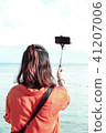 Woman standing taking a photo selfie on the sea 41207006