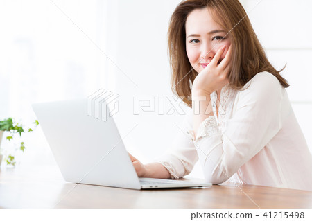 觀看一台便攜式計算機的婦女在屋子裡 觀看一台便攜式計算機的婦女在屋子裡 41215498