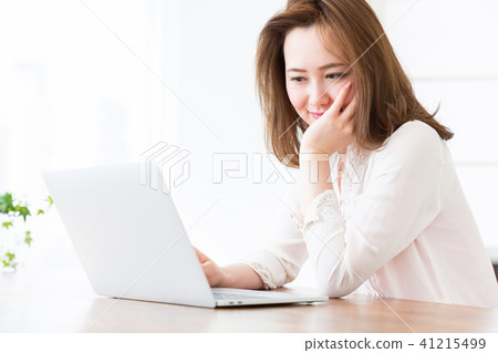 觀看一台便攜式計算機的婦女在屋子裡 觀看一台便攜式計算機的婦女在屋子裡 41215499