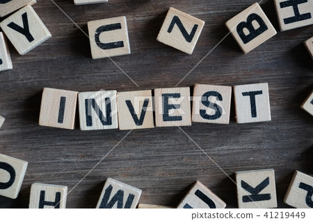 Word "INVEST" on cube dice on wood table 41219449