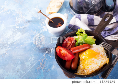 Homemade delicious breakfast on a pan with fried egg, toast, sausage, vegetable, black coffee Homemade delicious breakfast on a pan with fried egg, toast, sausage, vegetable, black coffee 41225525