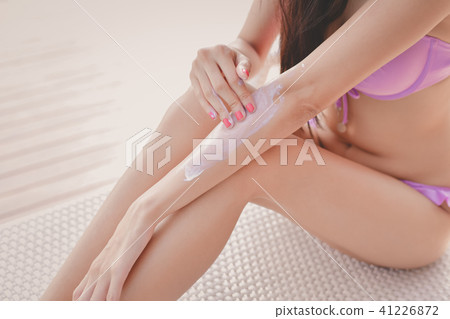 Swimsuit Concept. Beautiful girl in swimsuit is applying sunscre 41226872