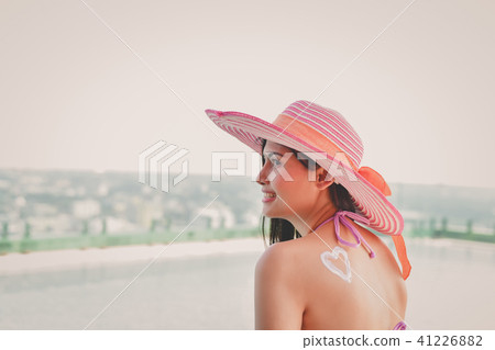 Swimsuit Concept. Beautiful girl in swimsuit is applying sunscre 41226882