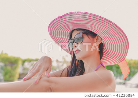 Swimsuit Concept. Beautiful girl in swimsuit is applying sunscre 41226884