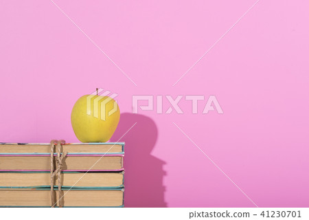 Yellow apple and old books with shadow. Pink background 41230701