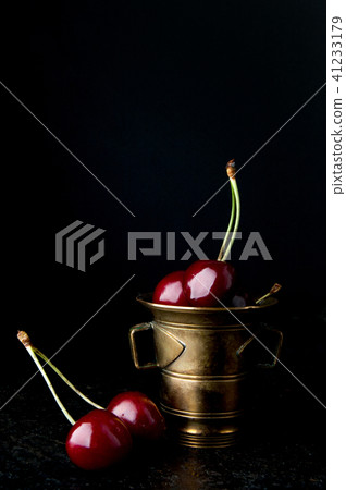 Cherries in bronze bowl on black background 41233179