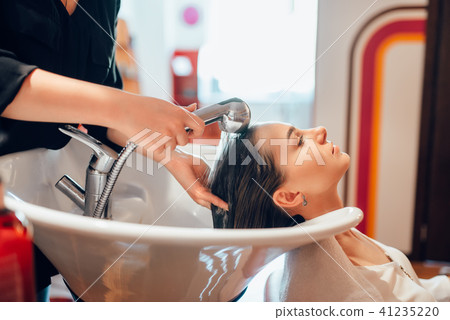 Hairdresser washes customer hair in basin Hairdresser washes customer hair in basin 41235220