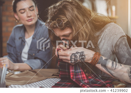 Focused male looking at cloth through magnifier Focused male looking at cloth through magnifier 41239902