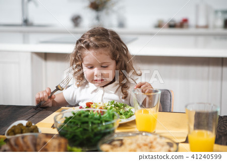 Cheerful female kid eating healthy food at home Cheerful female kid eating healthy food at home 41240599