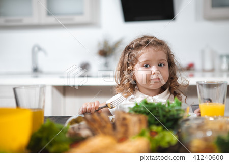 Cute curly girl having lunch in kitchen Cute curly girl having lunch in kitchen 41240600