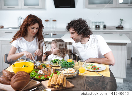 Mom and dad feeding little daughter in kitchen  41240643