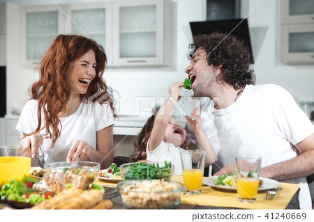 Carefree girl having fun with her parents in kitchen Carefree girl having fun with her parents in kitchen 41240669