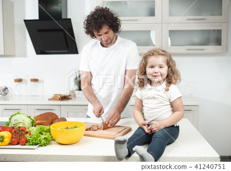 Cheerful kid watching her dad cooking Cheerful kid watching her dad cooking 41240751