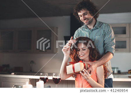 Glad woman receiving present from man at home  41240954