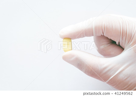 Hand in rubber glove with pill 41249562