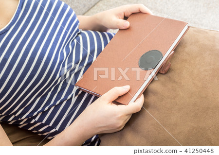 Woman holding a  book on the sofa Woman holding a  book on the sofa 41250448