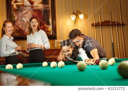 Young men and women playing billiards at office after work. 41251772